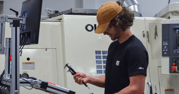 CNC machinist inspects part with calipers