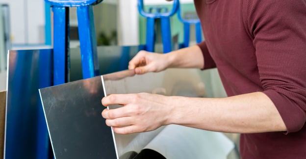 Production specialist pulls sheet metal for an operation