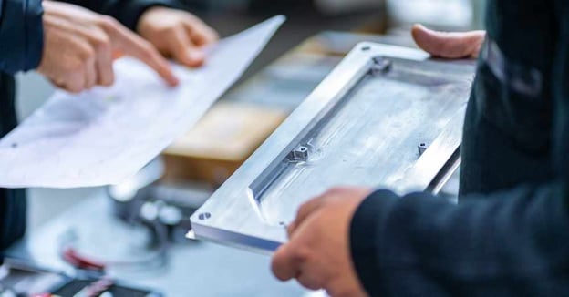 Engineers compare machined component to technical drawing