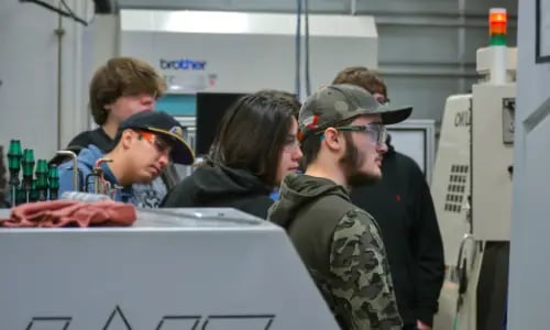 Students watch a CNC lathe at work