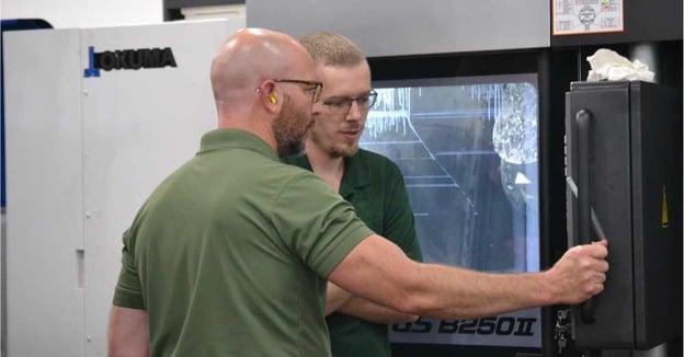 CNC programmer monitors mill-turn machine with CNC setup machinist