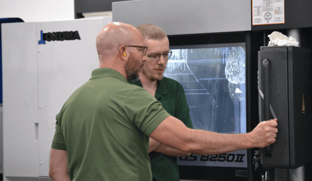 CNC programmer monitors mill-turn machine with CNC setup machinist