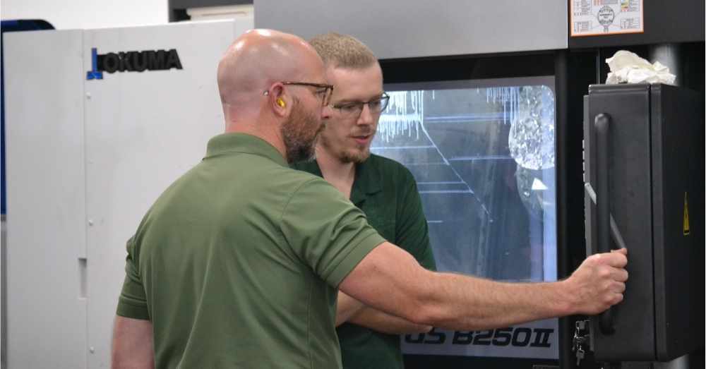 CNC programmer monitors mill-turn machine with CNC setup machinist